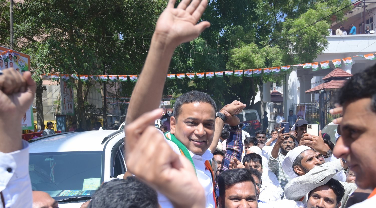 Mansoor Ali Khan among supporters on a Bengaluru street, hands raised in greeting.